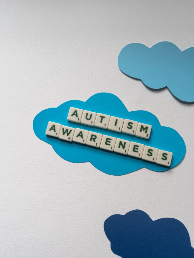 Autism awareness concept with wooden letter tiles on blue clouds
